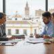 Abogados inmobiliarios en Sevilla reuniéndose con una pareja de clientes en una oficina moderna de Sevilla, con vistas al centro histórico de la ciudad.